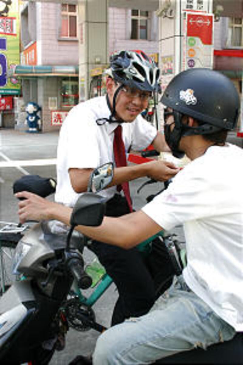Elder Chung-Hung Chen from Kaohsiung, Taiwan, tells a motor scooter rider on a street in Taichung ab