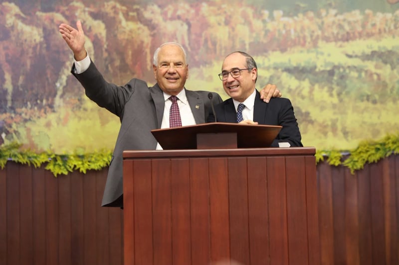 Elder Ronald A. Rasband of the Quorum of the Twelve Apostles waves to the congregation and puts his arm around Elder Valeri V. Cordón, a General Authority Seventy and president of the Caribbean Area, during a special conference in Santiago de los Caballeros, Dominican Republic, on Sept. 13, 2026.