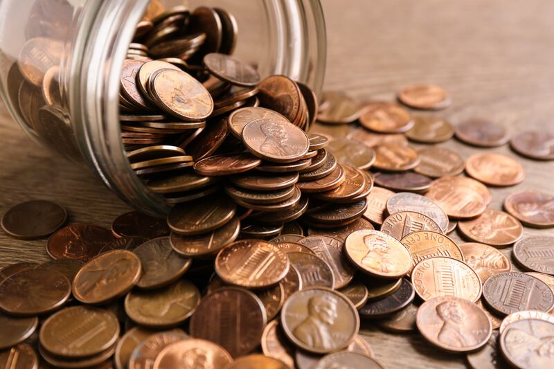 Small clear jar on its side with pennies spilling out