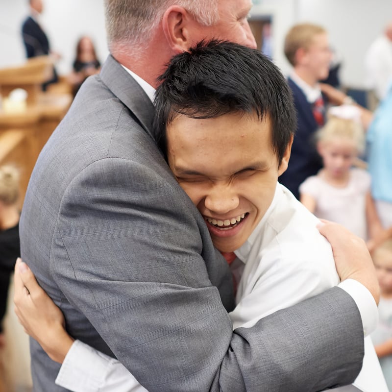 A young man who is blind hugs his bishop.