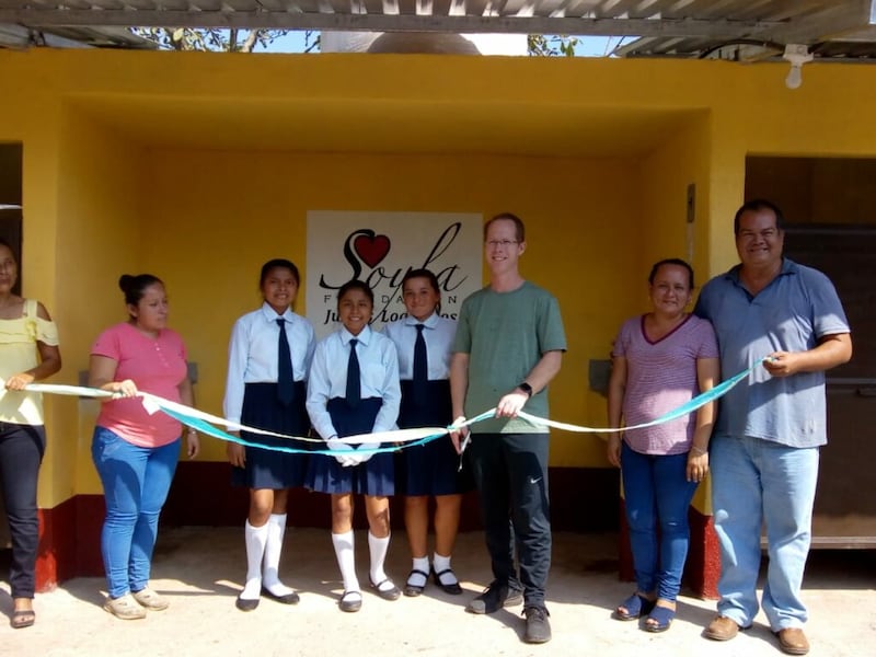Kenneth Grover, center right, stands with a group of students to cut a ribbon after completing a toilet building project for one of the schools where the SOYLA Foundation sponsors scholarships in Guatemala.