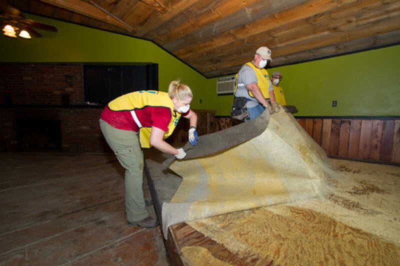 Members assist in removing damaged carpet from a home.