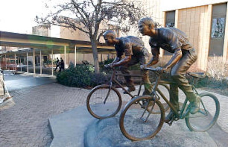 Missionaries walk by a bronze sculpture of missionaries on bikes.