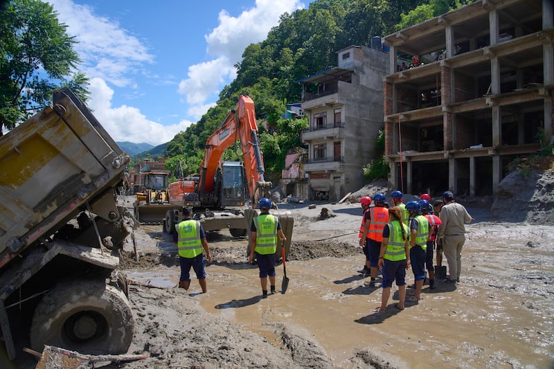 Earthmovers clear the debris from flash flooding in Nepal's Nuwakot district, Thursday, Aug. 27, 2026.
