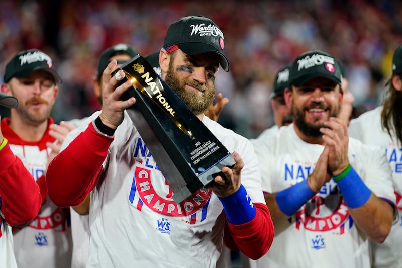 Philadelphia designated hitter Bryce Harper celebrates with the trophy after winning the baseball NL Championship Series.