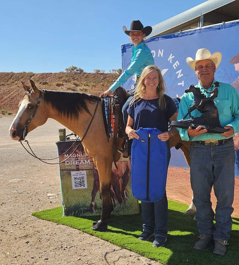 Brogan Hill and her horse, Quik Draw McGraw, pause for a photo with her mother Melinda Rumsey, and Bob Poplin, a mentor to Hill, who are holding Hill's champion trophies at the Intermountain Reining Horse Association Derby in Salina, Utah, in August 2023.