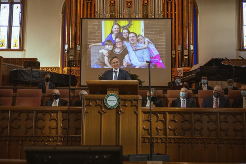 Kenneth L. Alford, a BYU professor of Church history and doctrine, speaks during the Tuesday, Feb. 15, 2022, Ensign College devotional in the Assembly Hall on Temple Square in Salt Lake City. On the screen is a photo of his daughter Suzanne, her husband Kendall, and their four children.
