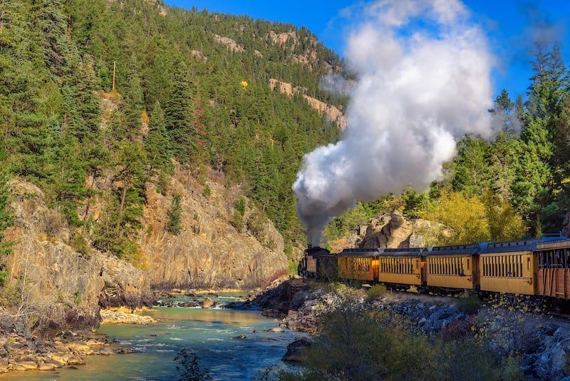 A historic steam engine train travels from Durango to Silverton through the San Juan Mountains along the Animas River in Colorado.