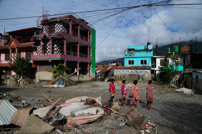 People walk past damage in the aftermath of flash floods in Devighat in the Nuwakot district in Nepal, Thursday, Aug. 27, 2026.