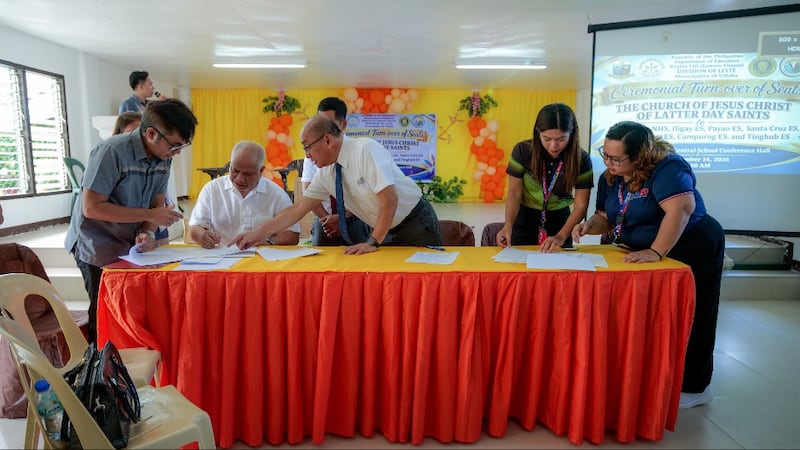Officials sign paperwork for a donation of classroom armchairs and medical equipment from the Church in Villaba, Leyte, Philippines, on Sept. 14, 2026.