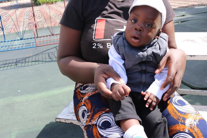 Samuel, at age one, seated on his mother's lap outside the Lewanika General Hospital in Mongu, Zambia. He was born premature in December 2024.