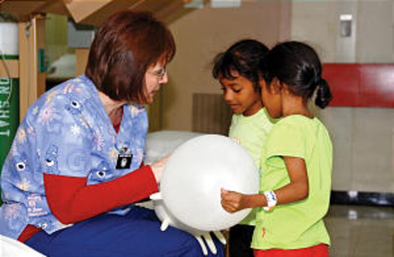 Nurse Laura Young of Honeyville, Utah, entertains two young Dominican sisters the night before their