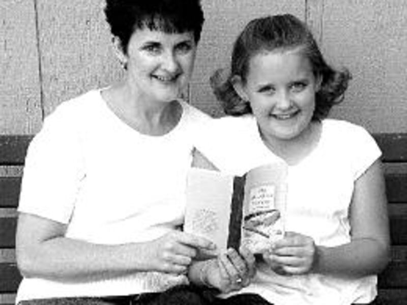 Heidi and Tiffany Larson look at the booklet Tiffany wrote: "My Mom Has Cancer."