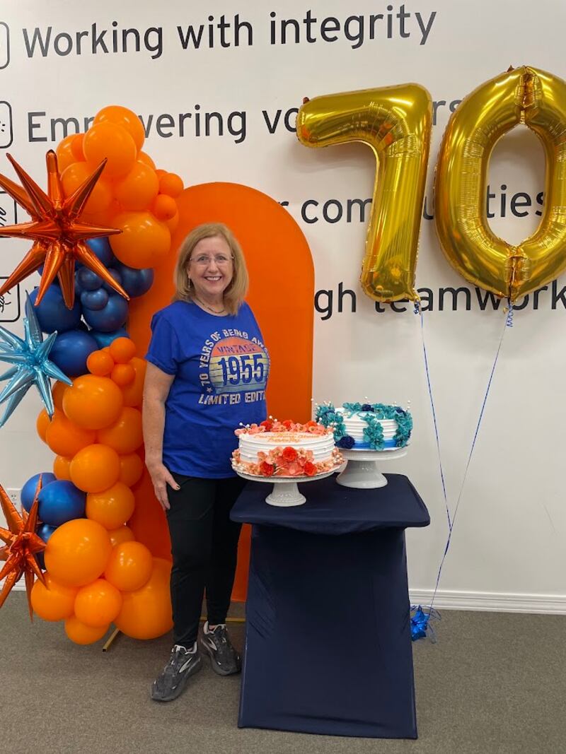 Gwynne Fullmer poses for a photo with birthday cakes and balloons while volunteering at Midwest Food Bank in Gilbert, Arizona, on Oct. 18, 2025, to celebrate her 70th birthday.