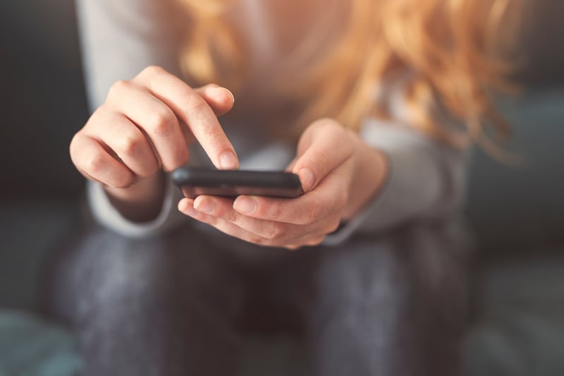 A young woman looks at her phone.