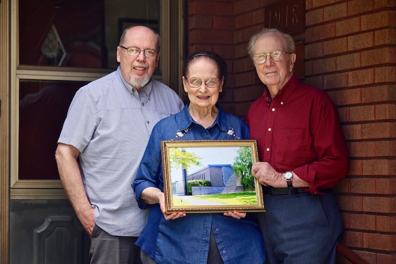 Elden and Picola Wood stand with their son, Alan, who accompanied his parents to Belgium where Elden supervised the building of the chapel shown in the photo.