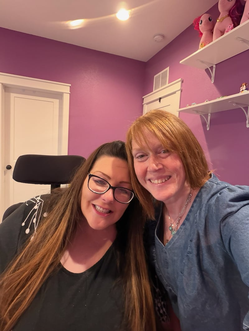 Nikki Peterson, right, poses with Angela Holmes in Peterson's home on July 11, 2026.