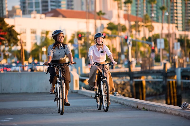 Two sister missionaries wearing helmets and riding bikes.