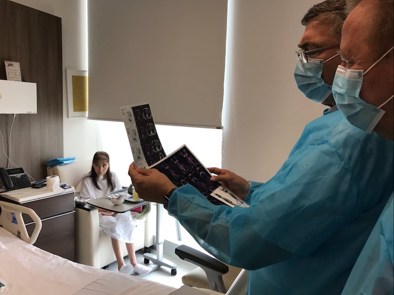 Doctors in Lima, Peru, review medical scans while Escarly Albujar rests in the back of the room.