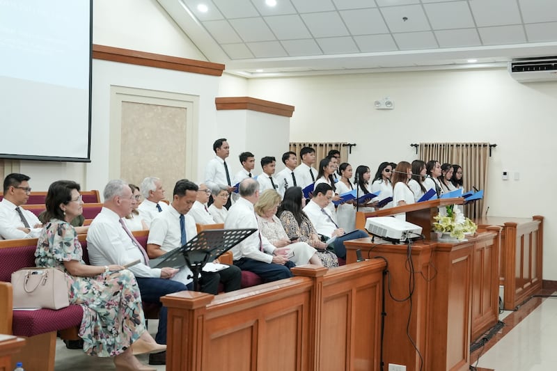 Elder Ulises Soares of the Quorum of the Twelve Apostles and his wife, Sister Rosana Soares (left), listen to a choir perform during a young adult devotion in Cebu on May 16, 2026.