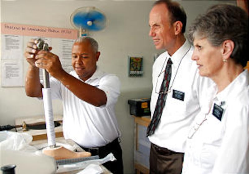 Danny Lopez demonstrates the assembly of a prosthetic leg to Elder Michael Francom and Sister Lorna