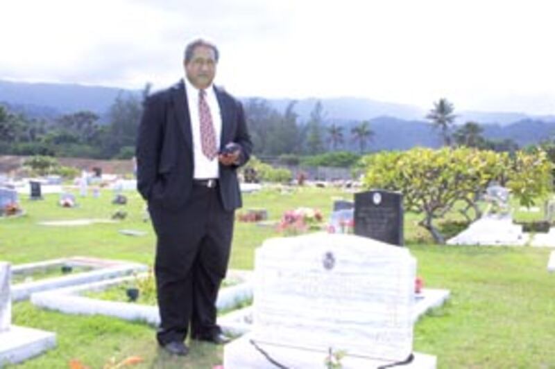 Pane Meatonga, president of the Laie Community Association, pauses beside grave of his grandfather d