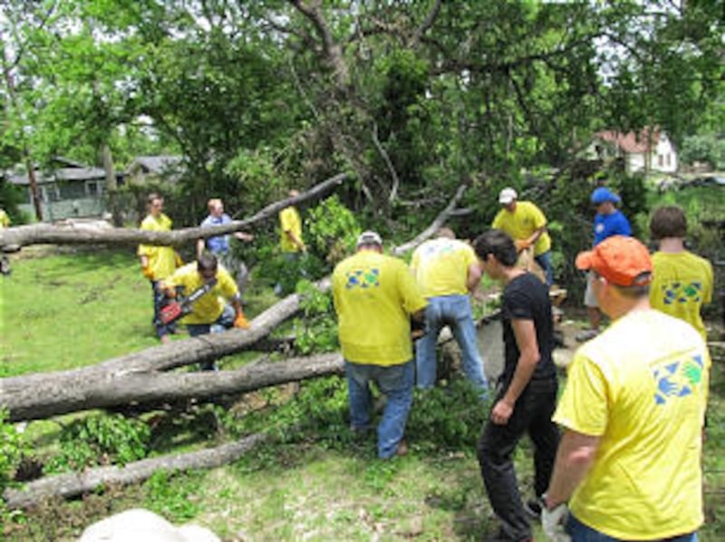 Mormon Helping Hands work crew uses chain saws to section a felled tree in a yard in Georgia. Member