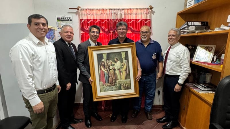 Elder Enrique Texeira, third from the left, and other local members meet with Paraguayan prison officials about a new ministry initiative and present a picture of the Savior.