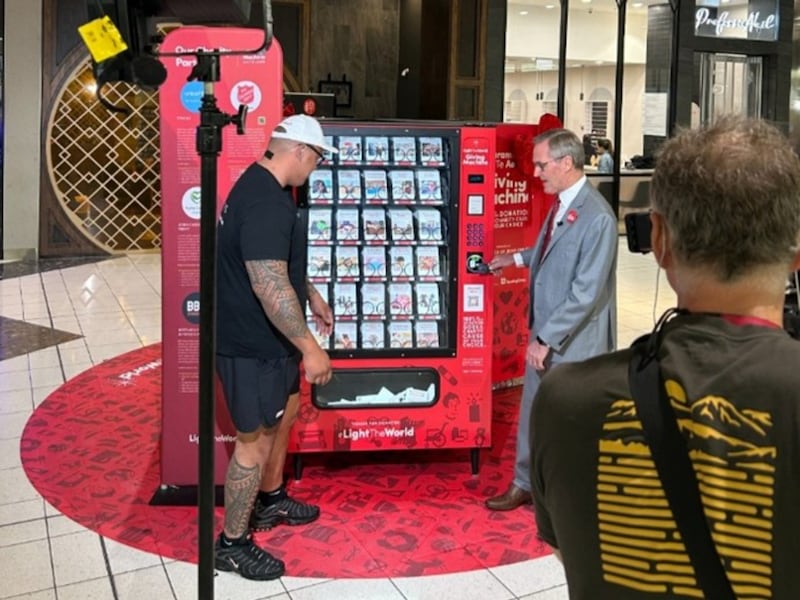 Dave Letele of BBM Motivation and Elder Peter F. Meurs, General Authority Seventy and president of the Church's Pacific Area, explain to TVNZ news how to use a Giving Machine on Tuesday, Dec. 9.