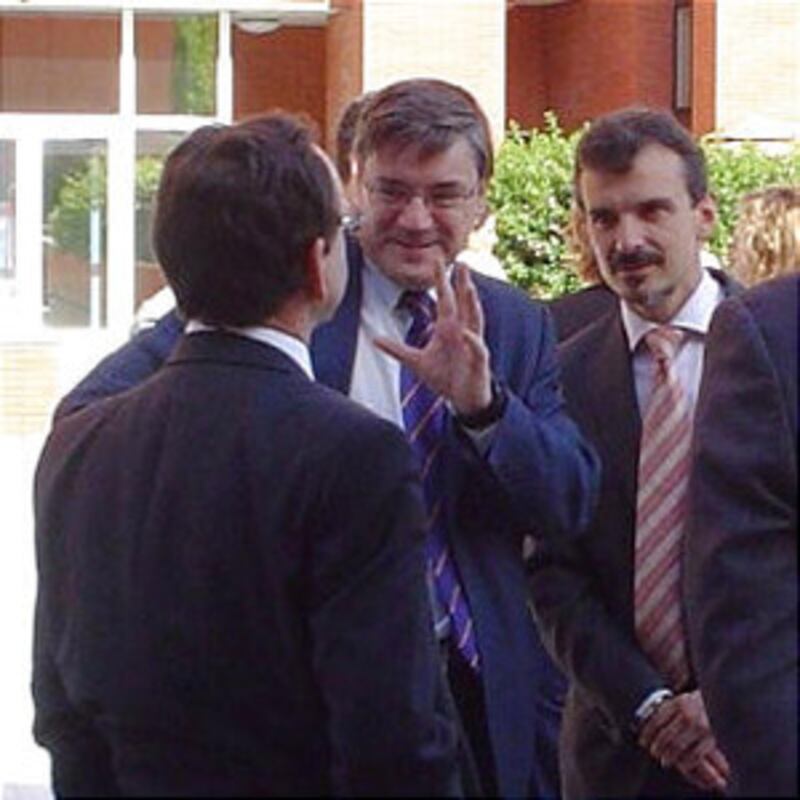 Elder Faustino Lopez,back to camera, converses with two officials from Spain's Ministry of Justice: