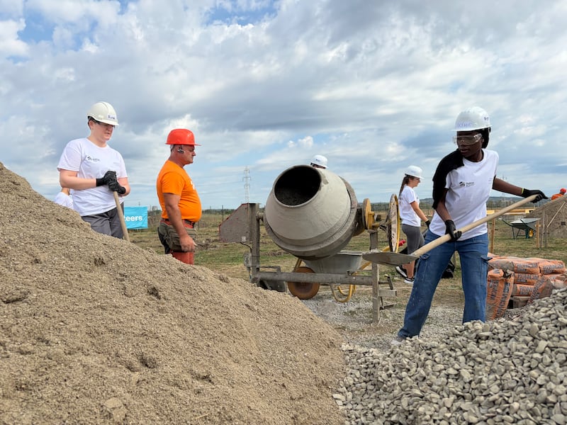 Young adults prepare concrete under the direction of a Habitat for Humanity Romania construction professional during a weeklong service project in Berceni, Romania, in August 2026.