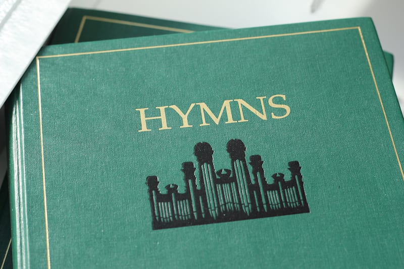 The Church’s green hymn book, focused on the title “Hymns” and the Tabernacle symbol.