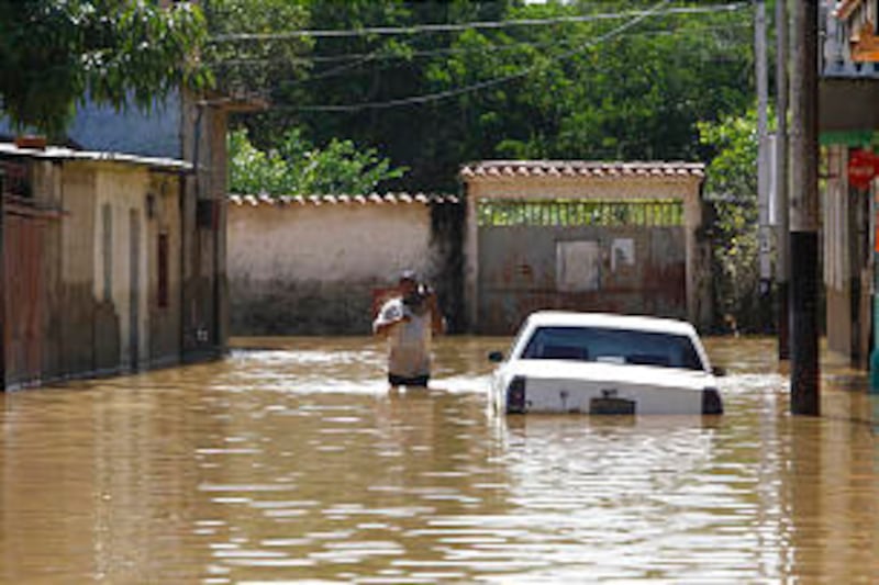 After weeks of torrential rain, a man wades along a flooded street in Higuerote, central Venezuela,