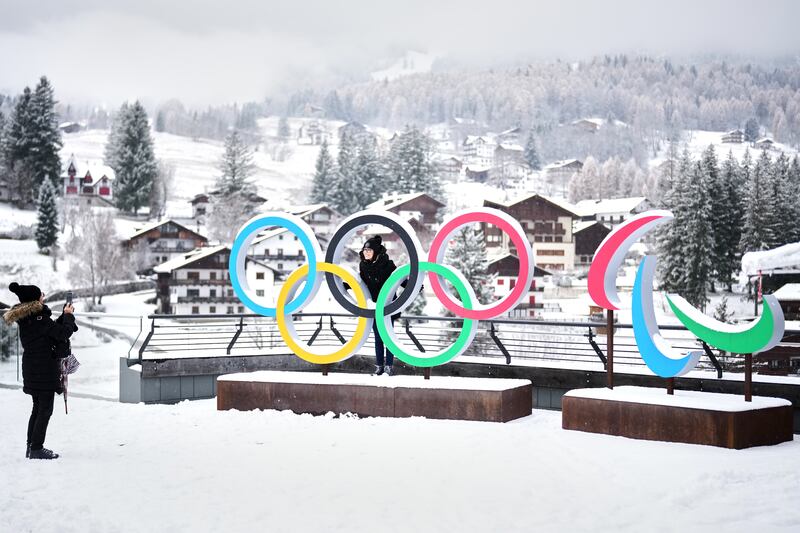 People take photos in front of the Milan Cortina Winter Olympics rings and Paralympics crescents, in Cortina D'Ampezzo, on Nov. 20, 2025.