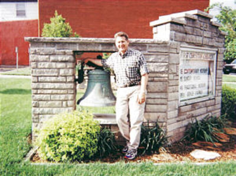 Fred E. Woods, co-author of a history of the disaster, stands next to steamboat's bell, owned by Fir