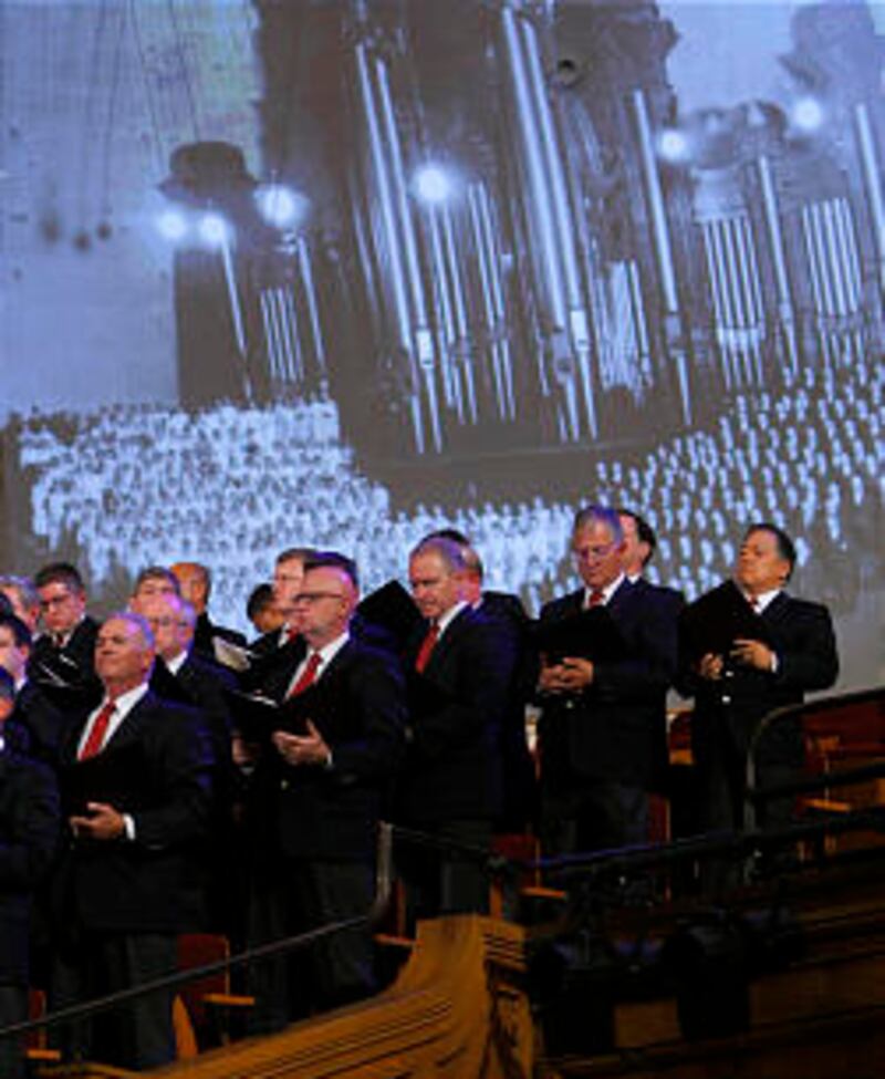 The choir sings with a historical photo projected in the background.