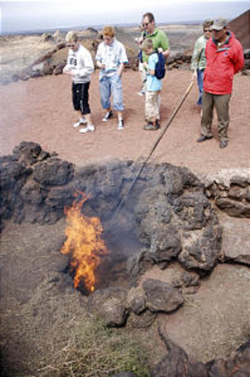 Tourists view heat vented up from heart of volcano to its top. Lanzarote is known as the island of