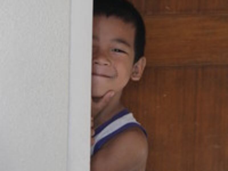 A child living in the San Juanico meetinghouse peeks around the corner the of the classroom where is
