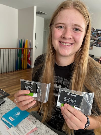 Adilaide Ohms, 18, holds up her missionary name tags. She will begin her missionary service on July 29, 2026.