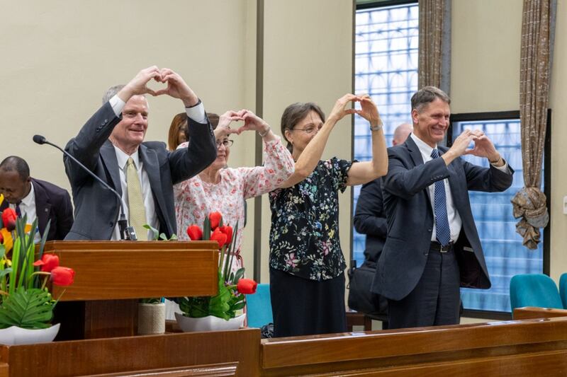 Elder David A. Bednar, Sister Susan Bednar, Sister Lynette Cook and Elder Carl B. Cook make heart signs with their hands toward young single adults in Kinshasa, Democratic Republic of the Congo, Saturday, March 14, 2026.