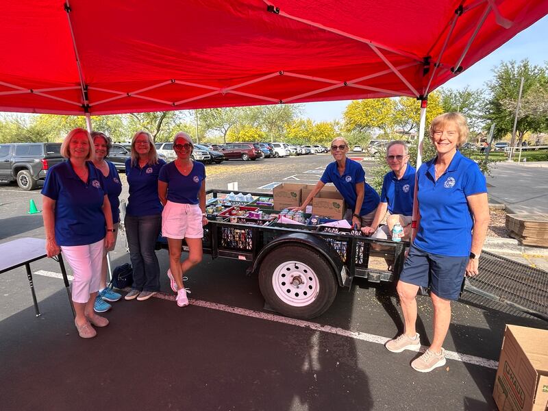 Volunteers at the "5K to Feed the 5k" event stand next to a trailer full of donated food in Anthem, Arizona, on March 28, 2026.