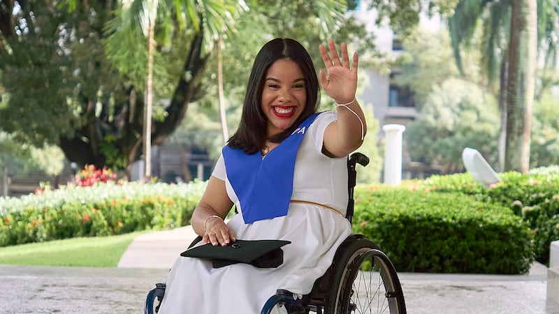 Sidney Peralta waves to the camera after receiving a degree in industrial psychology from the Open University for Adults.