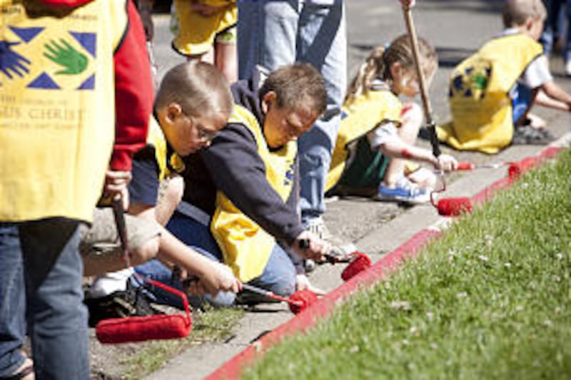 Wearing adult-sized Mormon Helping Hands yellow vests, a cadre of children gives service while rolli