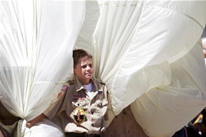 A boy scout helps handle the cover protecting the Mormon Battalion monument.