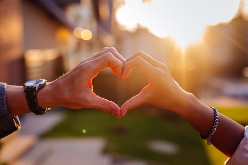 A couple hold their hands in the shape of a heart.