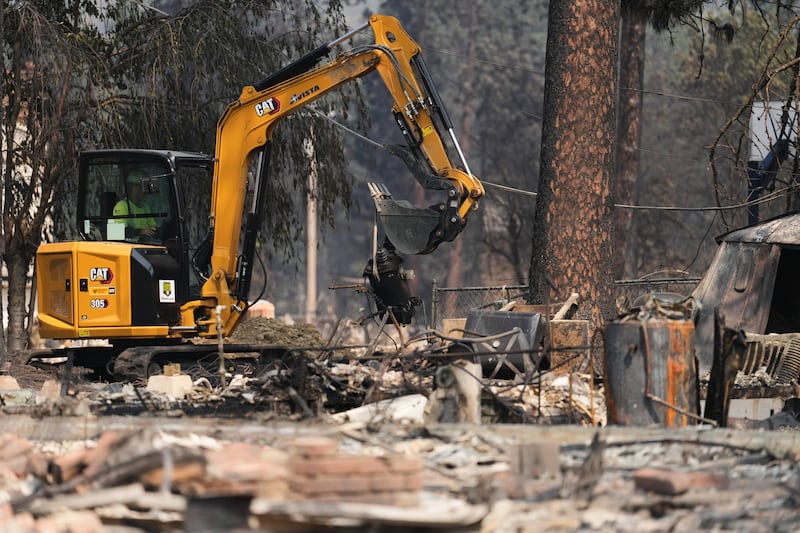 Crews work near several burned down houses after a wildfire hit the northwest part of Spokane, Washington, Tuesday, Aug. 4, 2026.