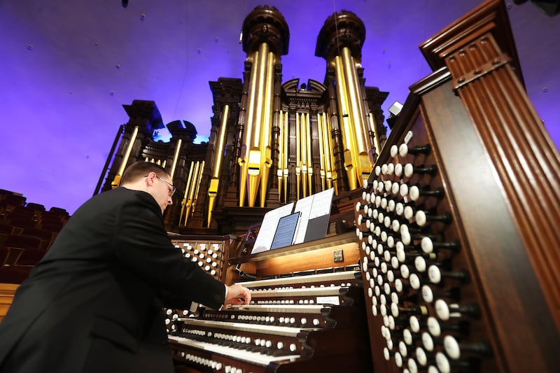 Organist Brian Mathias plays the Tabernacle organ and the organ pipes are visible in the background.
