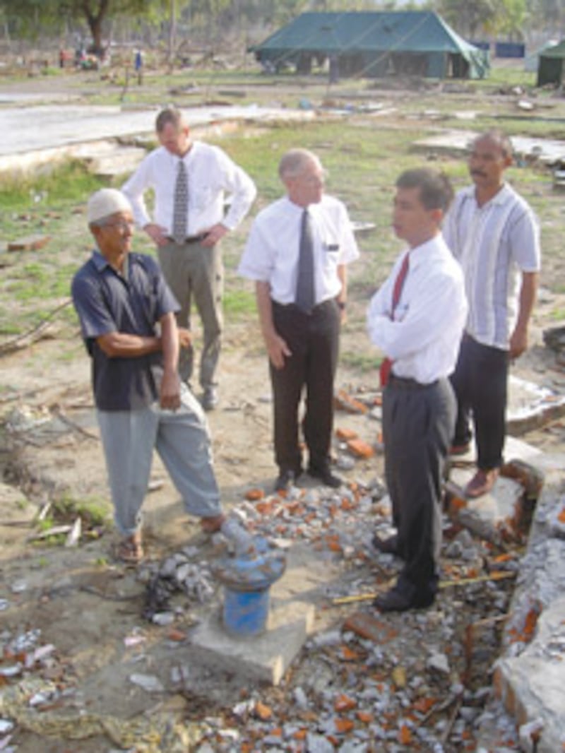 Elder Subandriyo, front right, and Elder Thomas Palmer, middle, view damage in Indonesia after tsuna