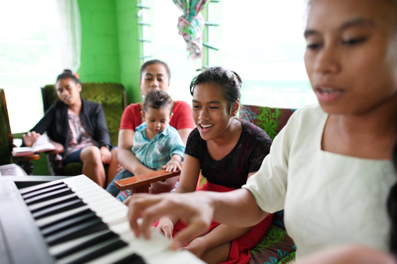 A family sings at home as one daughter plays on a keyboard.