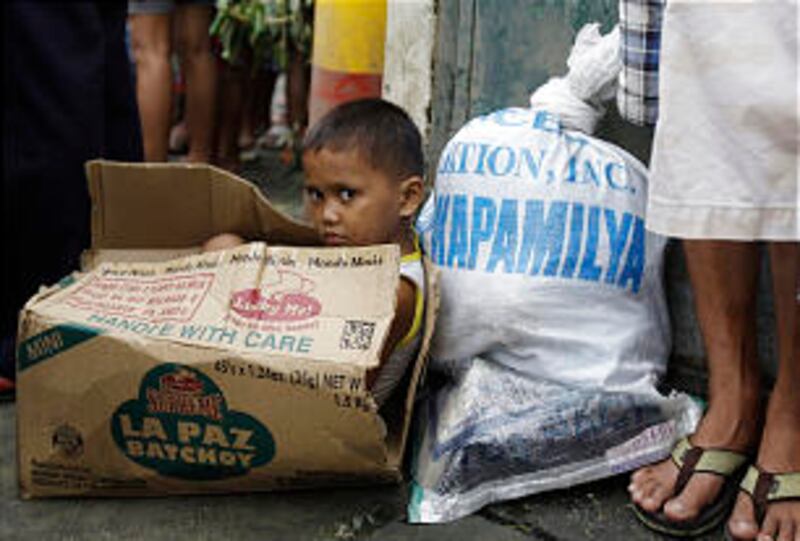 A Filipino boy sits inside an empty carton as he waits for his parents to receive relief goods in an